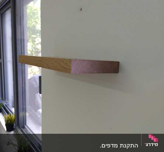 מדף עץ מותקן על קיר לבן